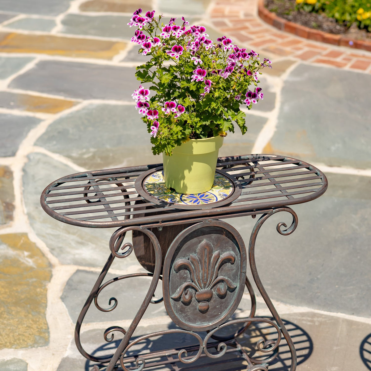 Close view of one metal stand holding a flowerpot, with a mosaic tile inset in its tabletop.
