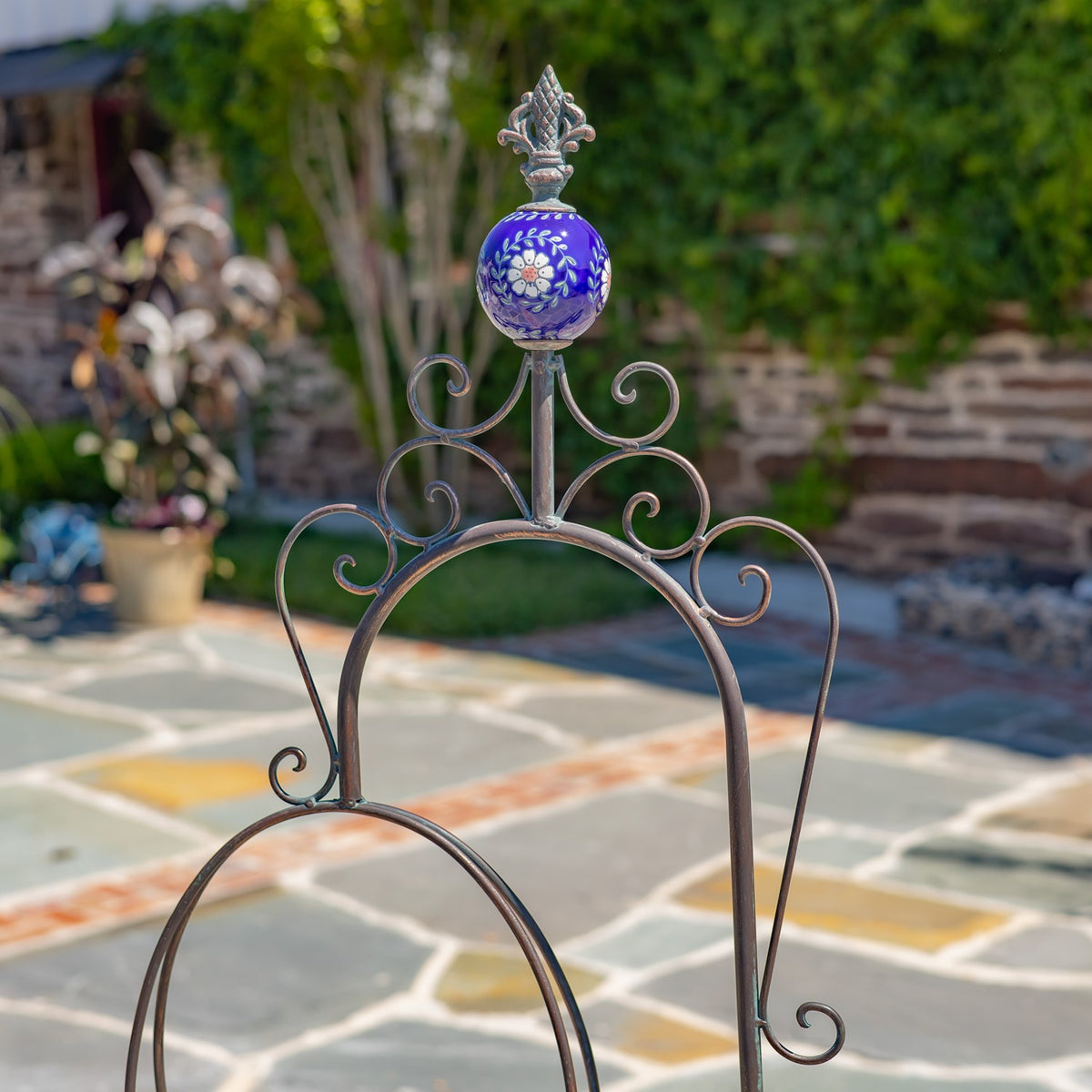Close-up of the stand’s curled metalwork and blue floral finial