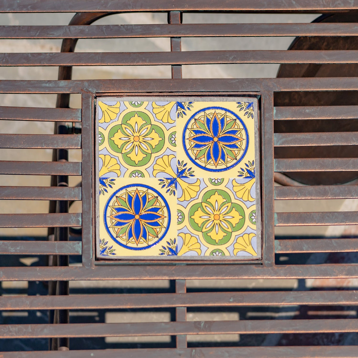 Square tabletop inset with blue, yellow and green floral patterns framed by dark metal slats.