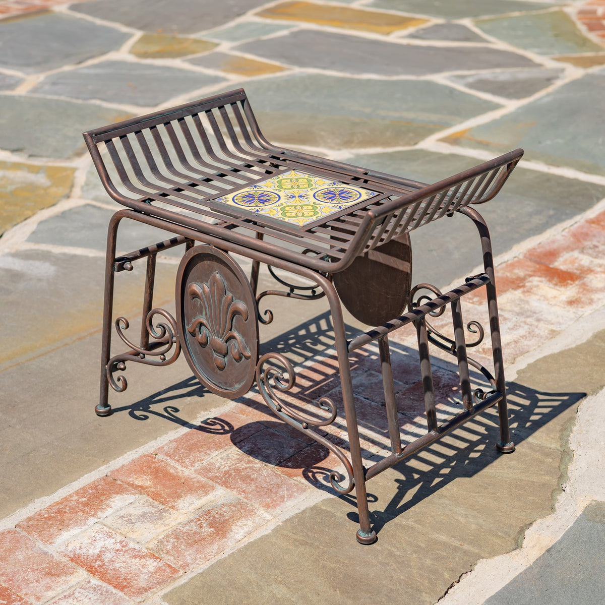 The chair from the other side, with curved slatted edges, mosaic seat tile, and metal scroll details.
