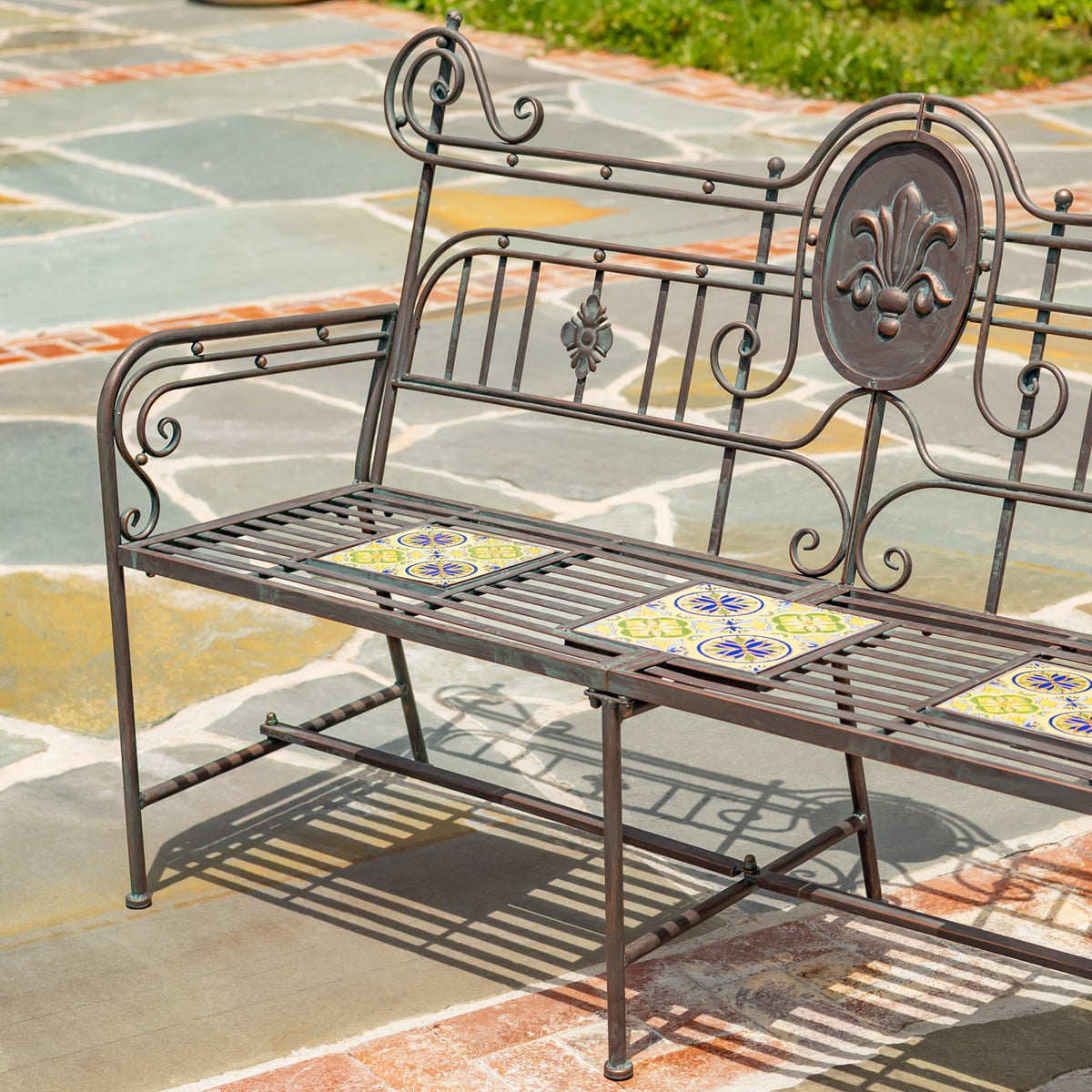 Closer angled view showing the bench's curled arms, metal slat seat, and colorful mosaic inserts.