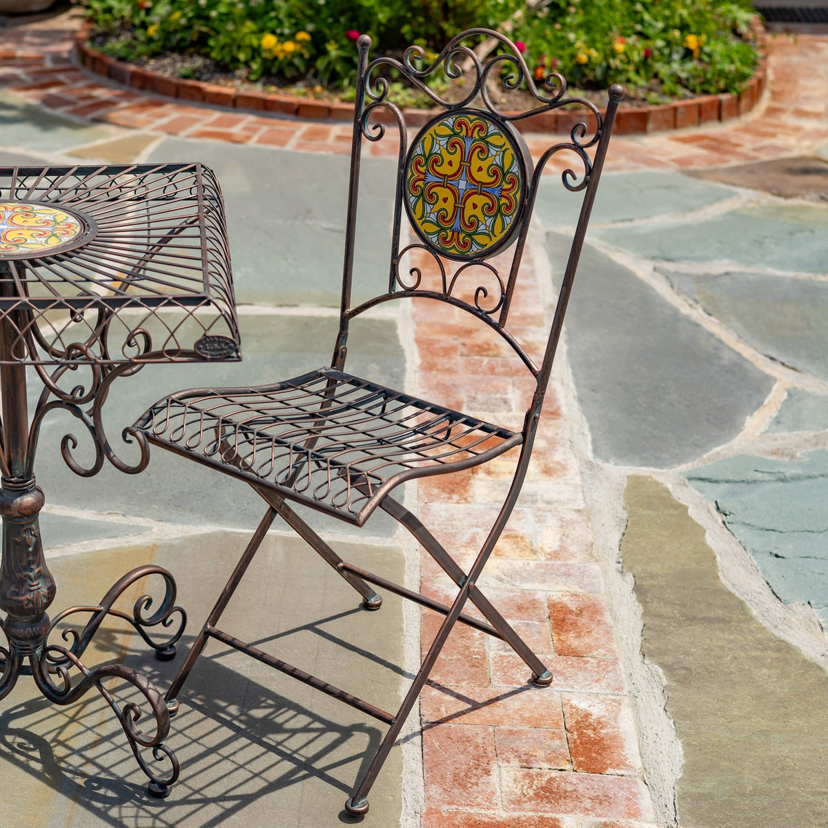 Folding metal chair with a colorful round mosaic backrest and curled iron details.
