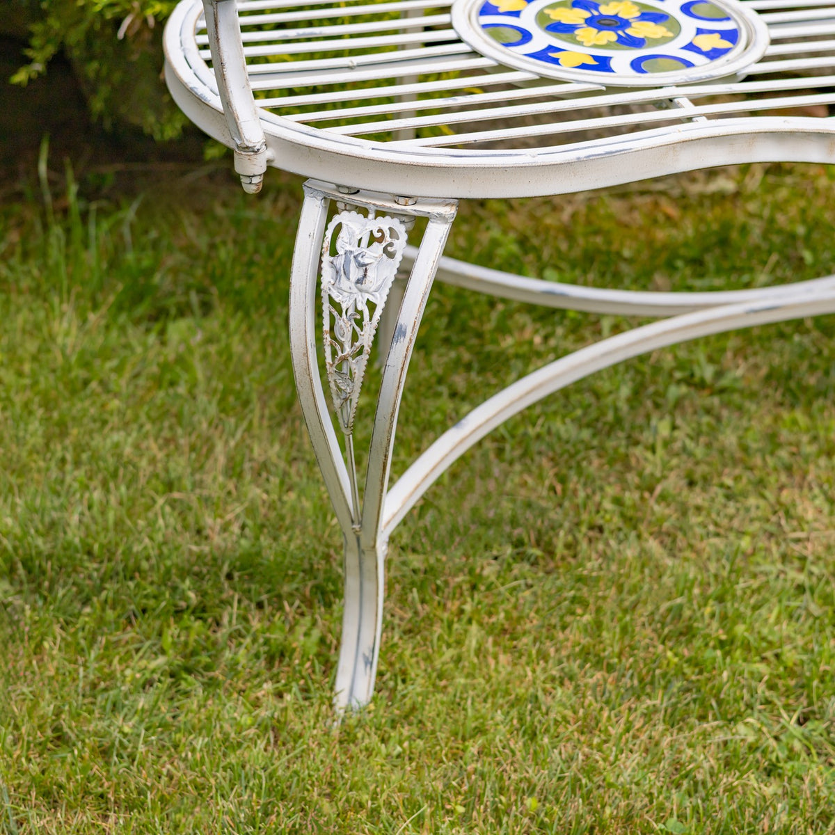 Close-up of a decorative cutout on the bench leg beneath the slatted seat.