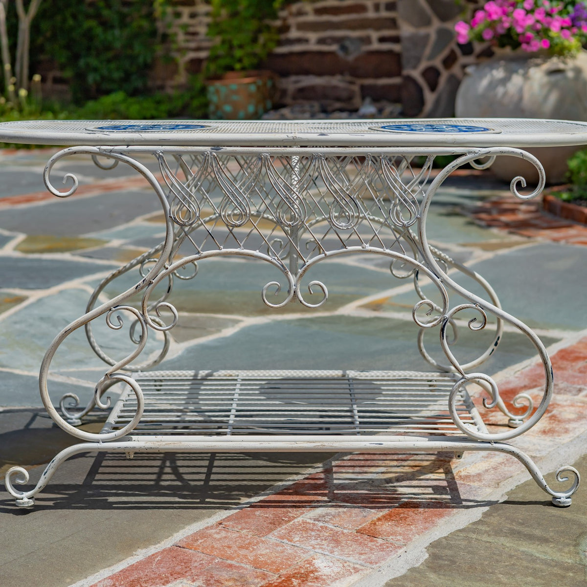 Side view highlighting the table’s ornate metalwork, oval top, curled feet, and lower shelf.