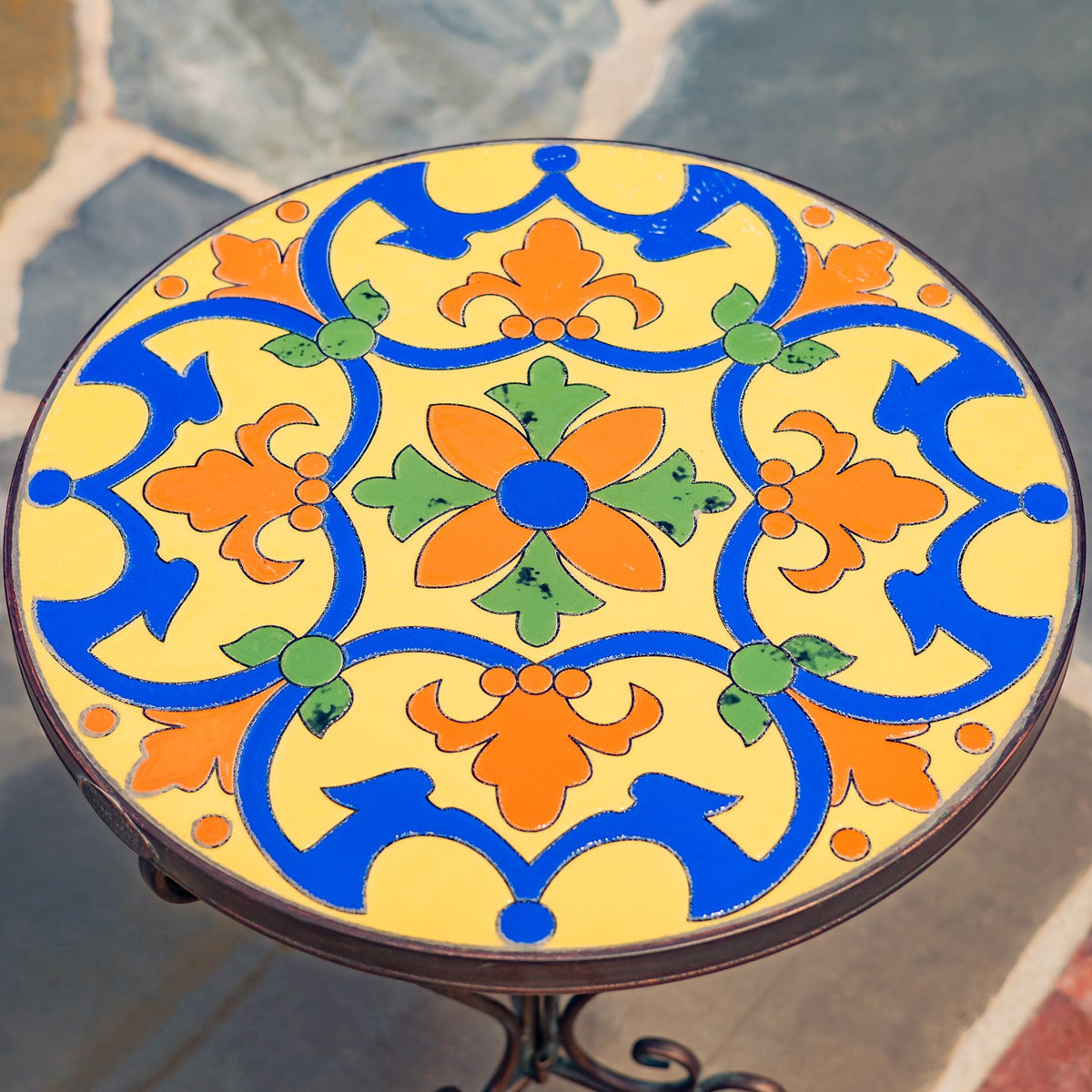 Close view of the round tabletop's colorful floral mosaic pattern and dark rim.