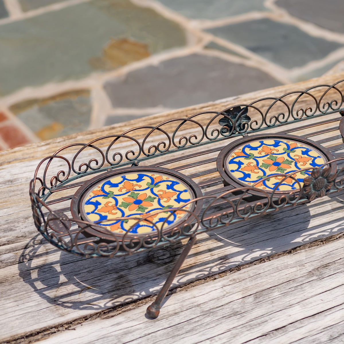 Closer angled view of the stand’s patterned mosaic panels, scrolling rails, and metal legs.