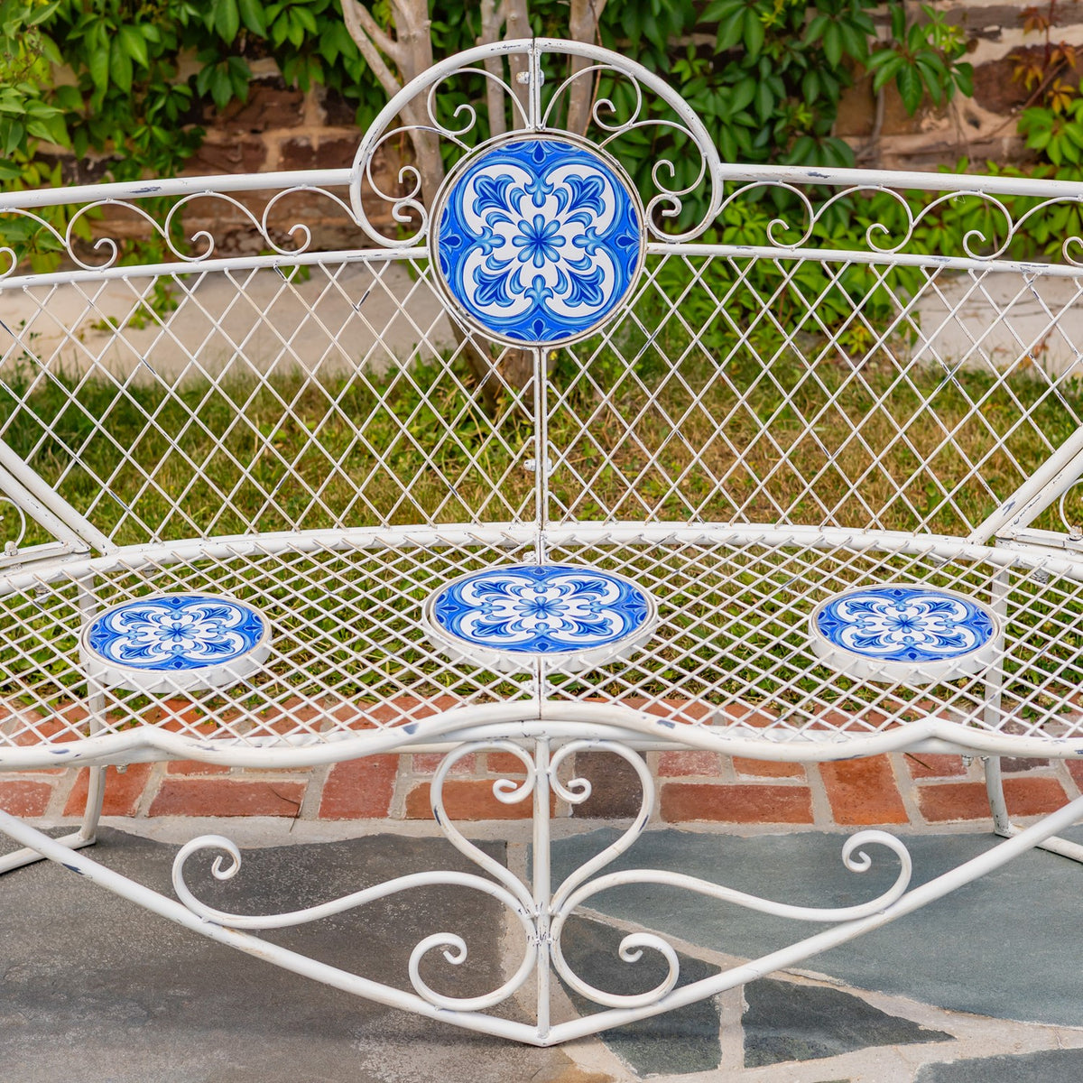 Closer view of the blue patterned mosaic accents against the bench’s white metal lattice and scrollwork.