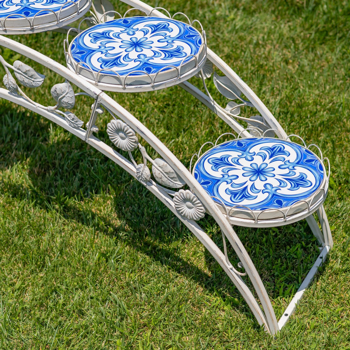 Close view of blue floral mosaic platforms, curved metal rails, leaf accents and flower-shaped ornaments.