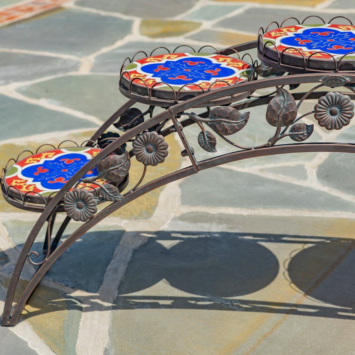 Close view of the stand’s curved metal frame, floral ornaments, and patterned mosaic shelves.