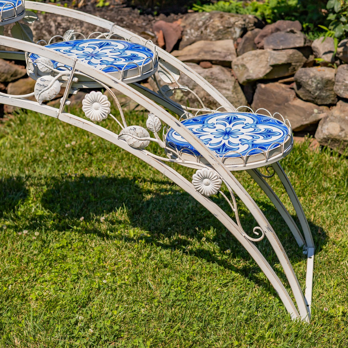 Close-up of blue patterned mosaic platforms and raised flower-shaped details on the white arched frame.
