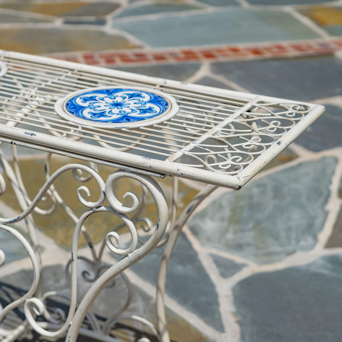 Close view of the slatted tabletop, blue patterned mosaic inset, and curled metal edging.
