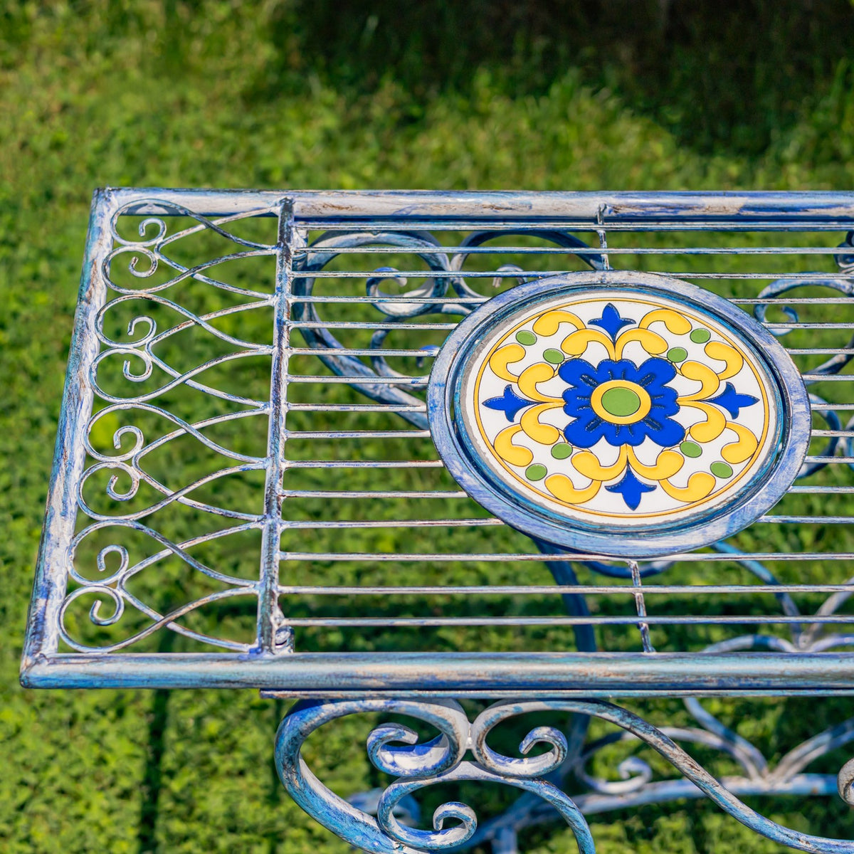 Close-up of the tabletop’s blue, yellow and white floral mosaic medallion among narrow metal slats.