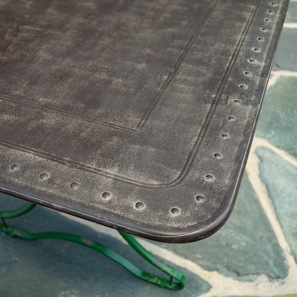Close-up of the dark tabletop showing its inset border, rounded corner and circular -like details.
