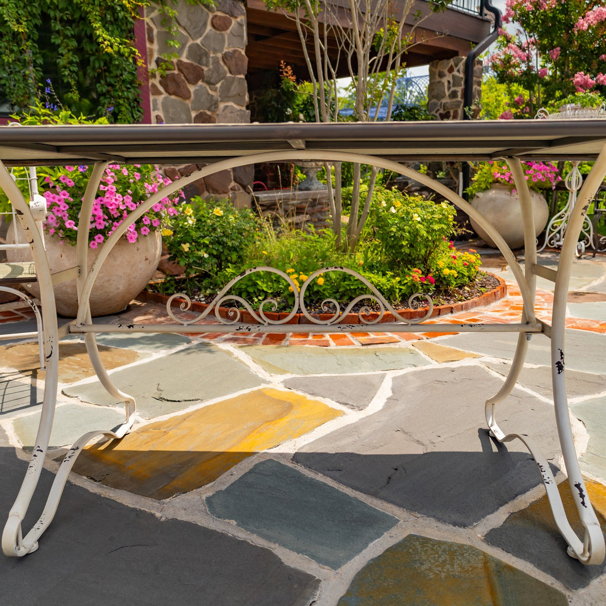 Low close-up of the white table’s curved metal legs and decorative scrollwork beneath the tabletop.