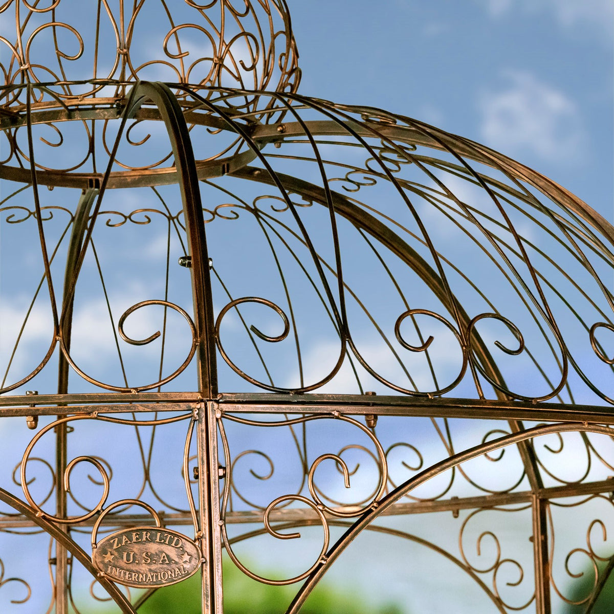 Angled close-up of bronze-toned iron roof ribs, decorative curls, and a small metal plaque.