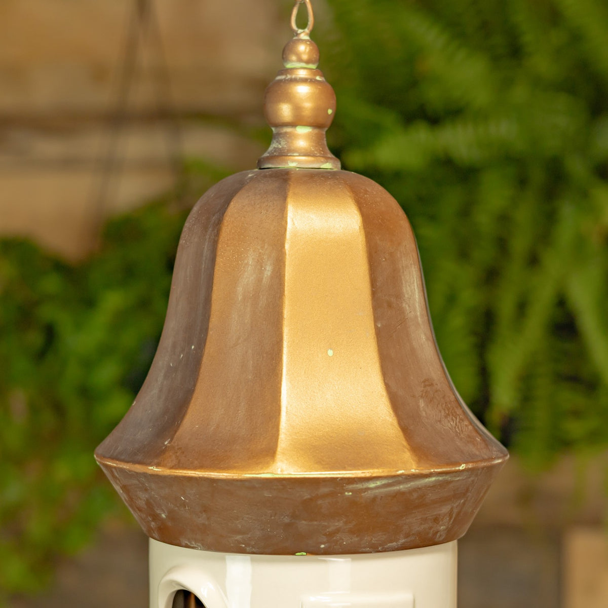 Close-up of the birdhouse’s curved copper-tone roof and decorative hanging loop.