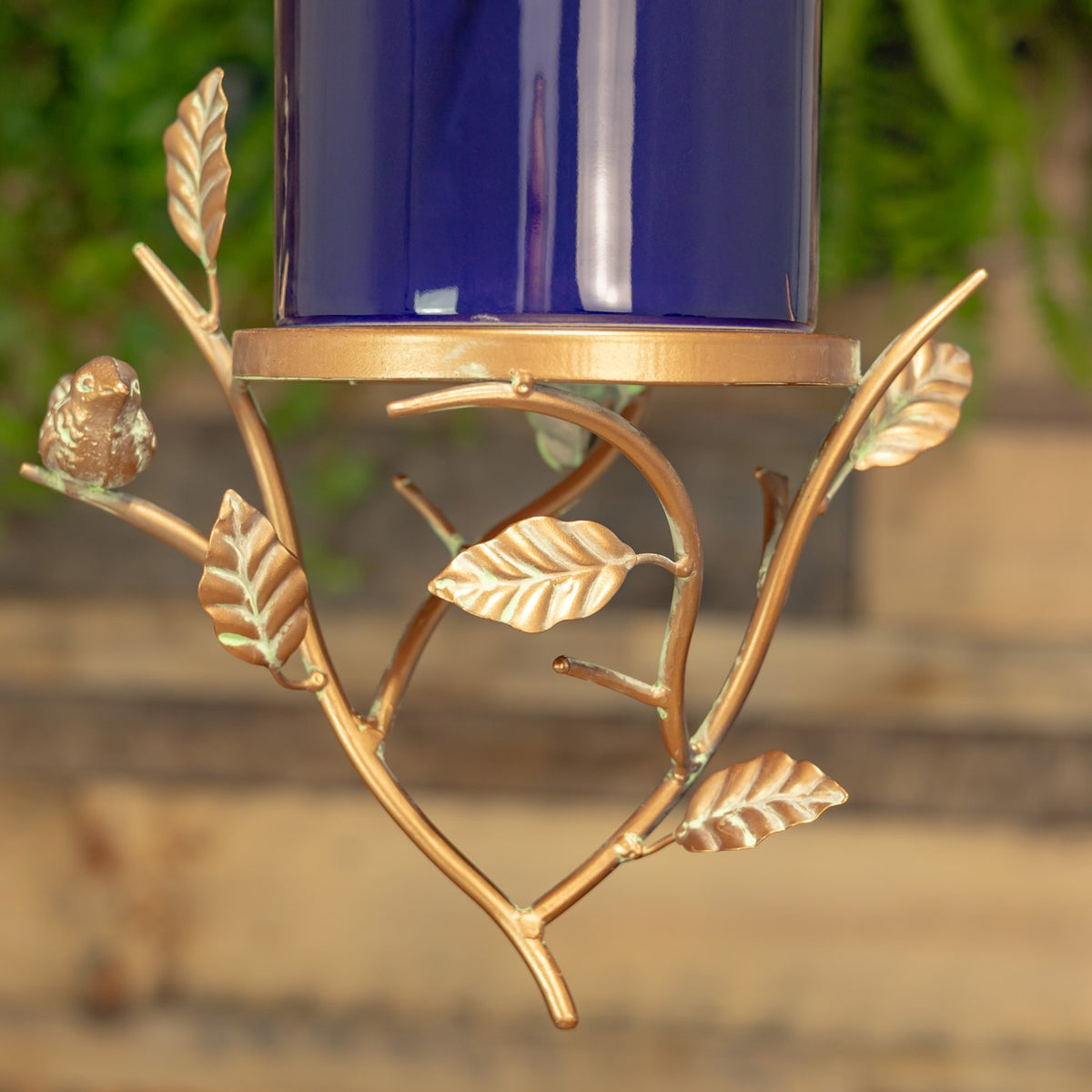 Curved copper-colored branches and sculpted leaves form the decorative stand beneath the birdhouse.