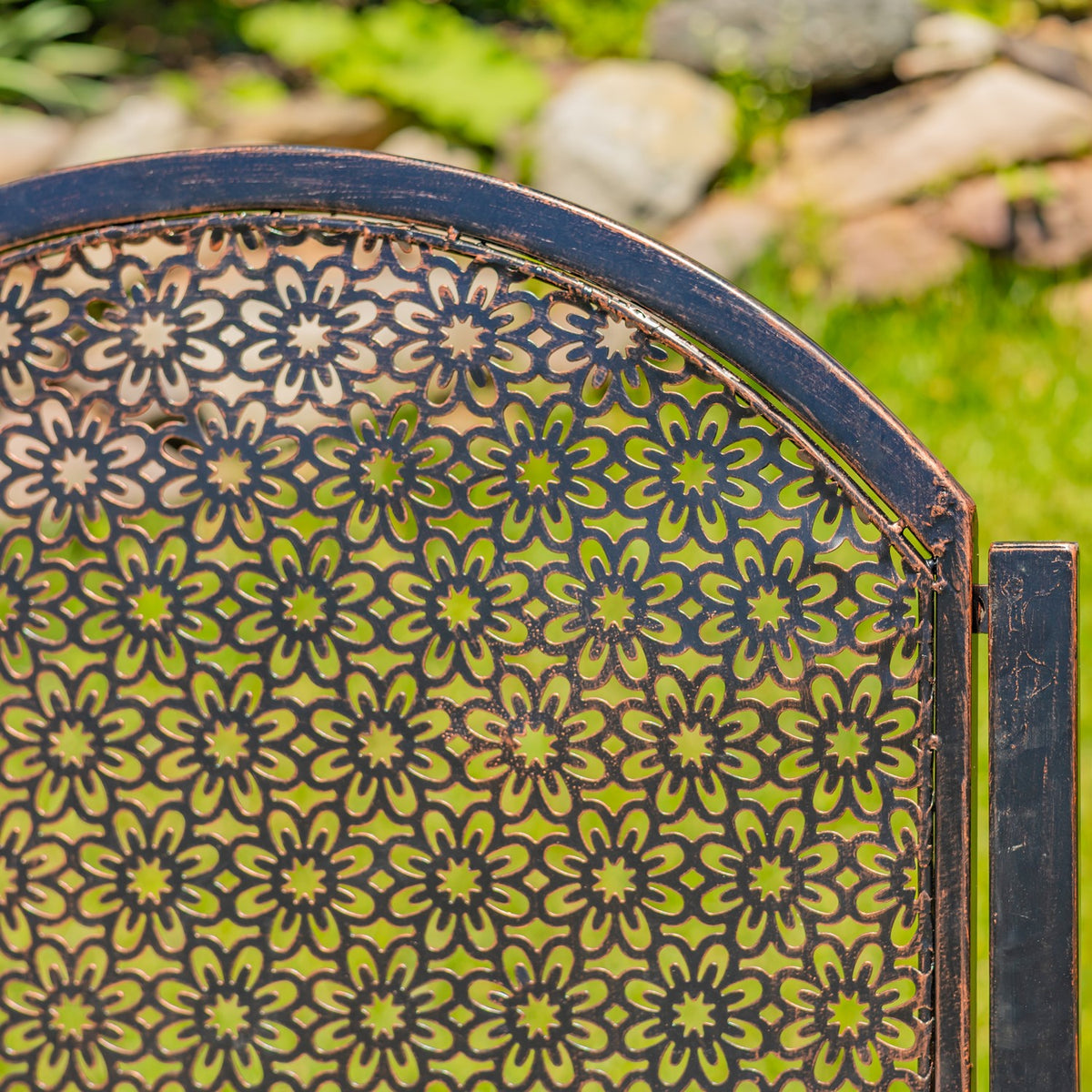 Close-up of the chair’s arched backrest with repeating floral cutouts and a dark bronze-toned frame.