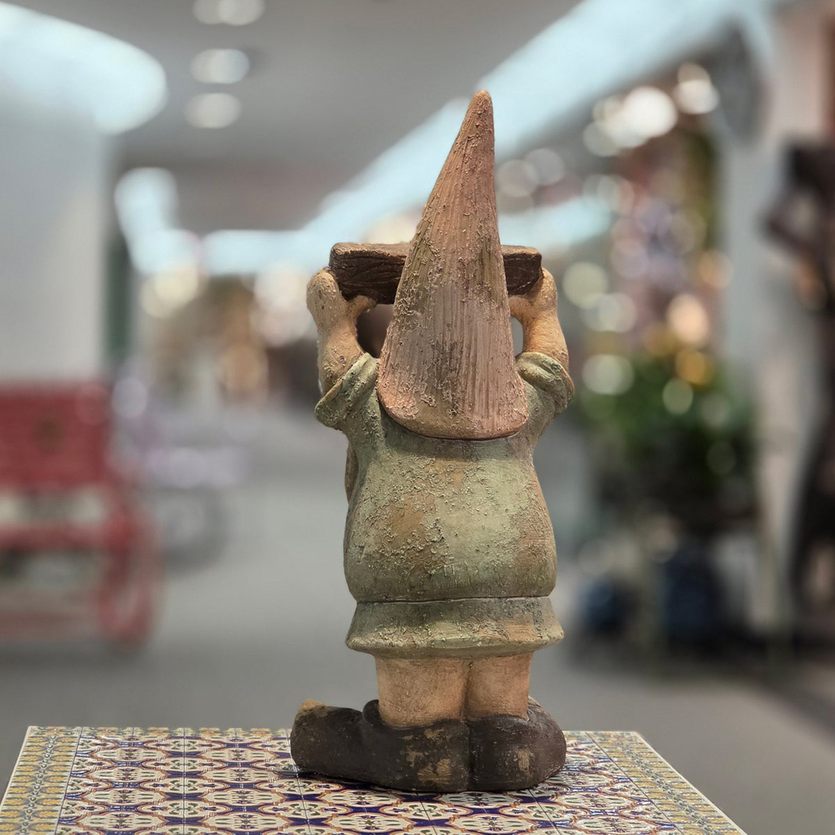 Back view of the garden gnome showing its pointed hat and green outfit