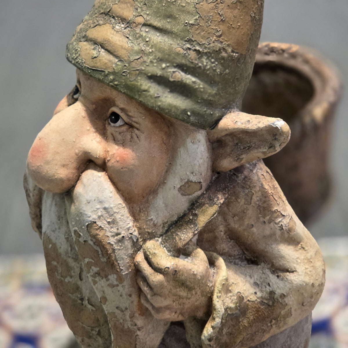 Close-up of the gnome's weathered face, pointed hat, hand, and back basket