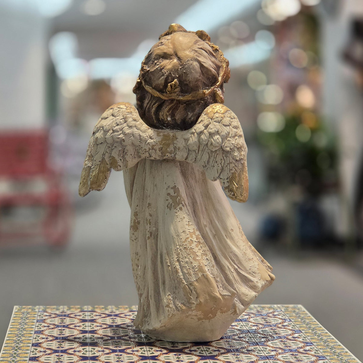 Rear view of distressed angel figurine showing its wings and flowing robe