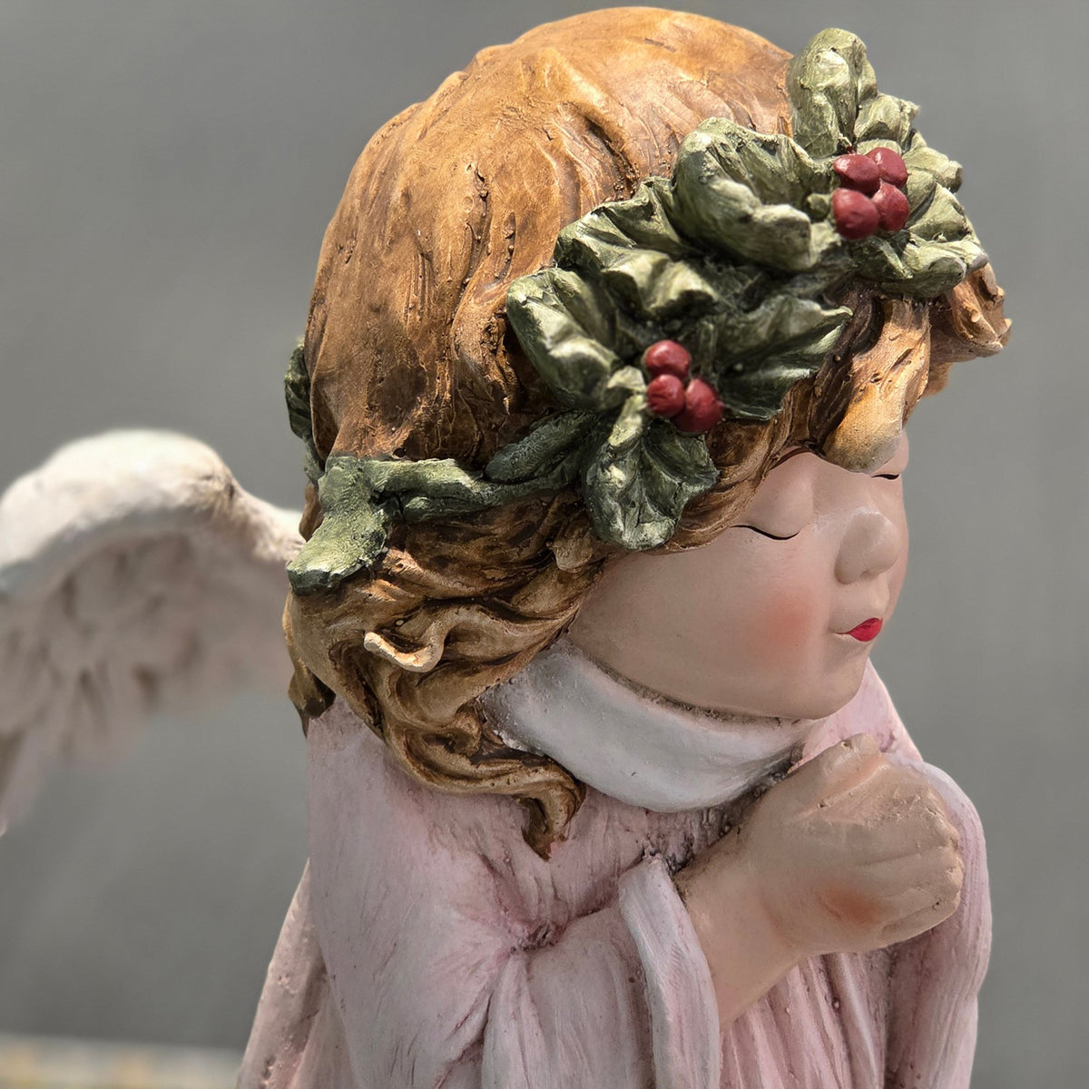 Close-up of the angel's holly wreath crown, brown hair and praying face