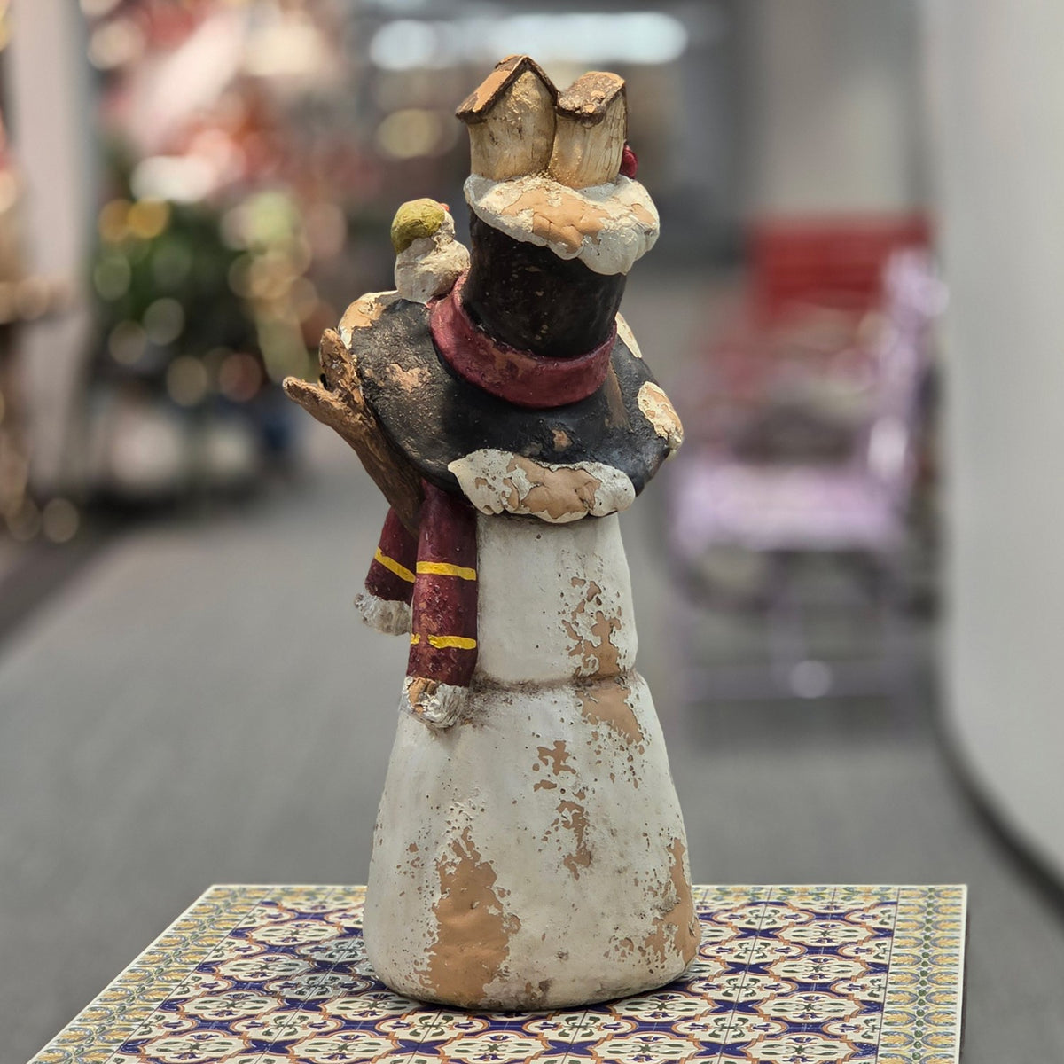 Rear view of the snowman figurine showing its tall hat and scarf