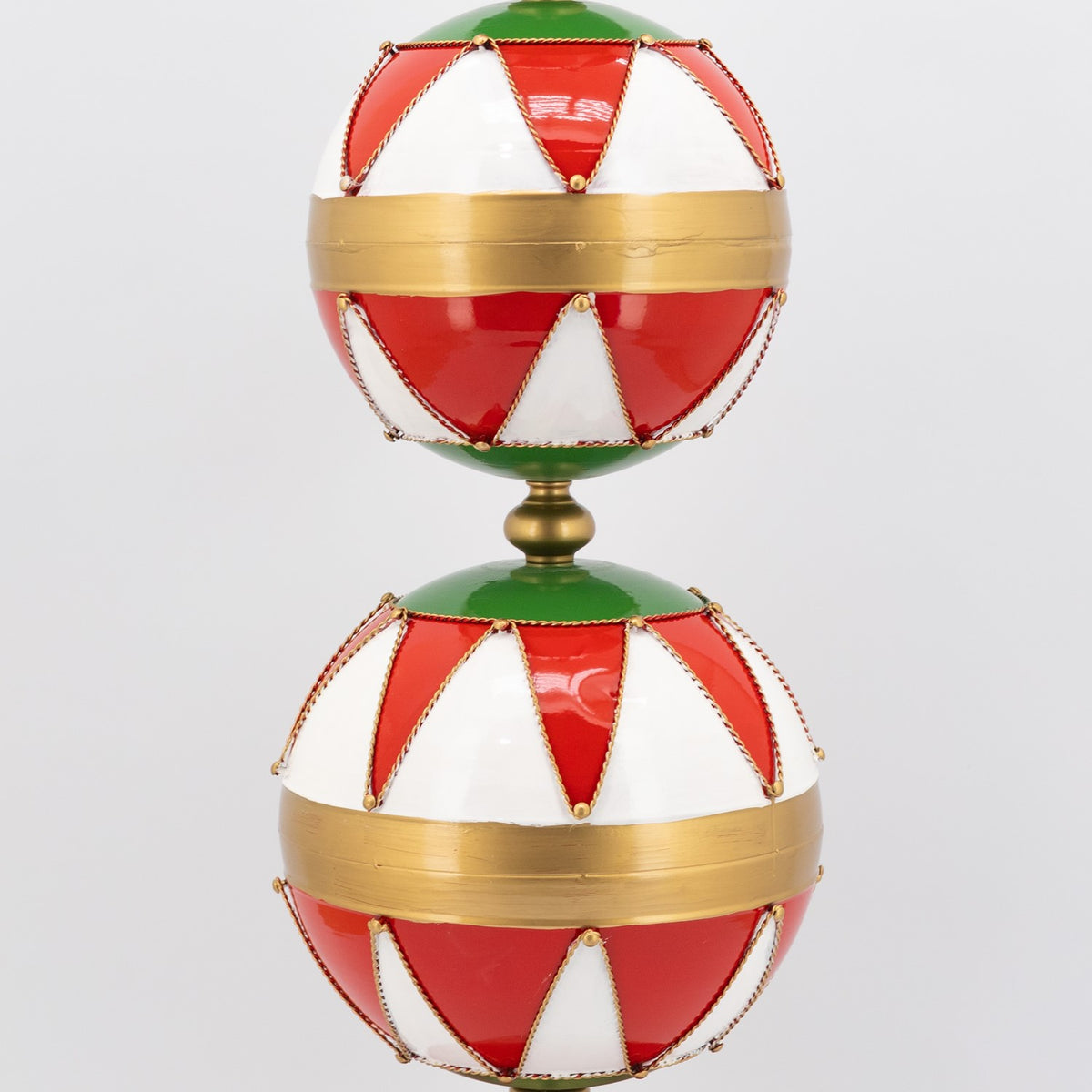 Close view of two stacked red-and-white ornaments with broad gold bands and green connectors.