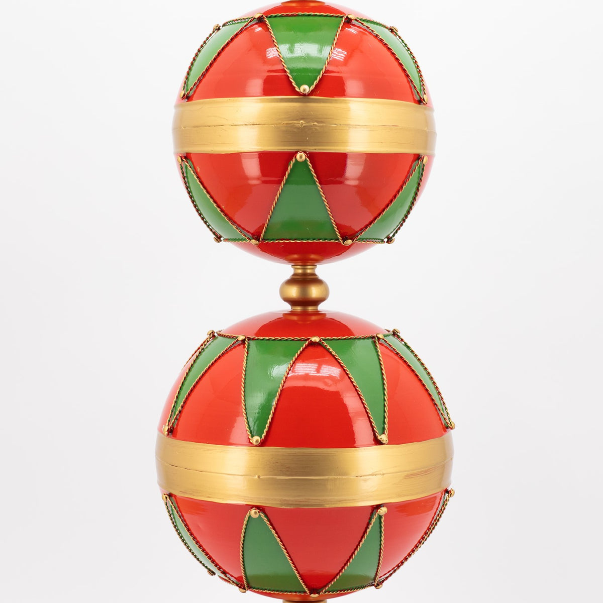 Two stacked red and green patterned spheres, each wrapped with a wide gold band.