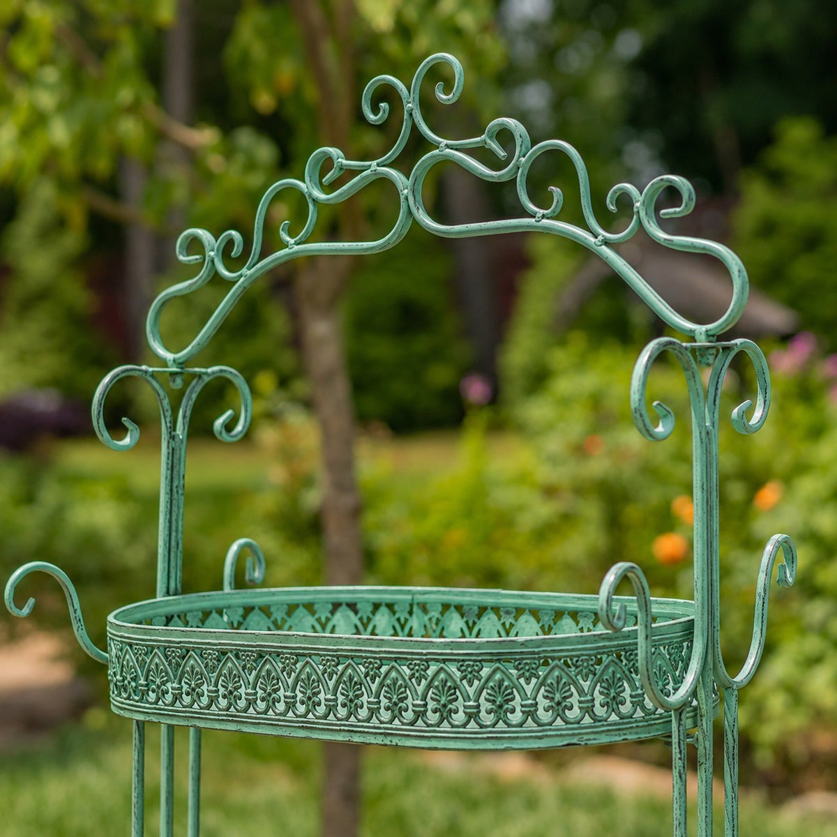 Close-up of the plant stand’s curled iron arch and patterned upper shelf.
