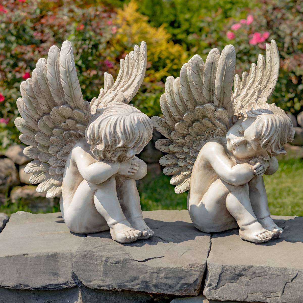 Back and side views of two sitting cherub statues on stone