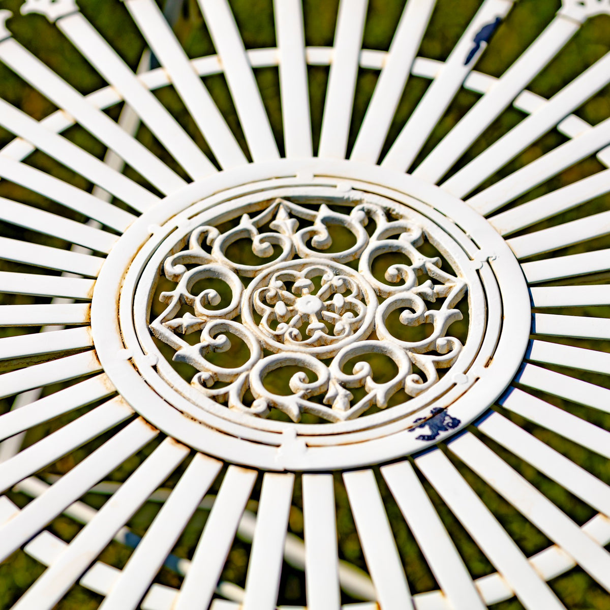 Close-up of the table’s round center medallion with raised scrollwork and radiating white metal spokes.
