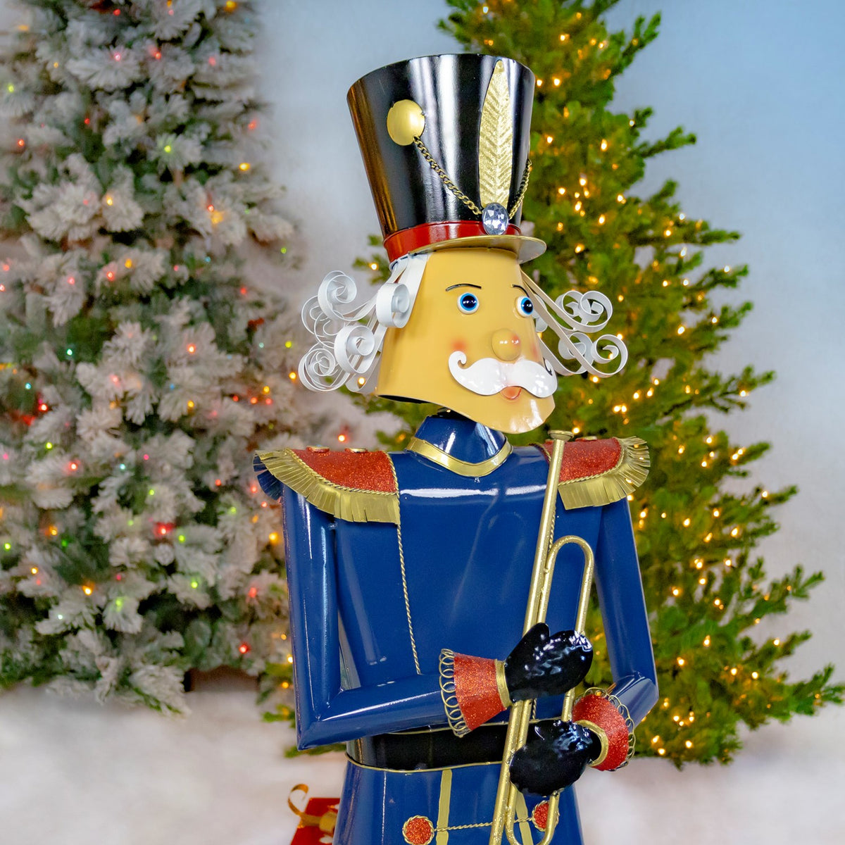 Three-quarter view of the blue nutcracker soldier holding a trumpet beside a tree