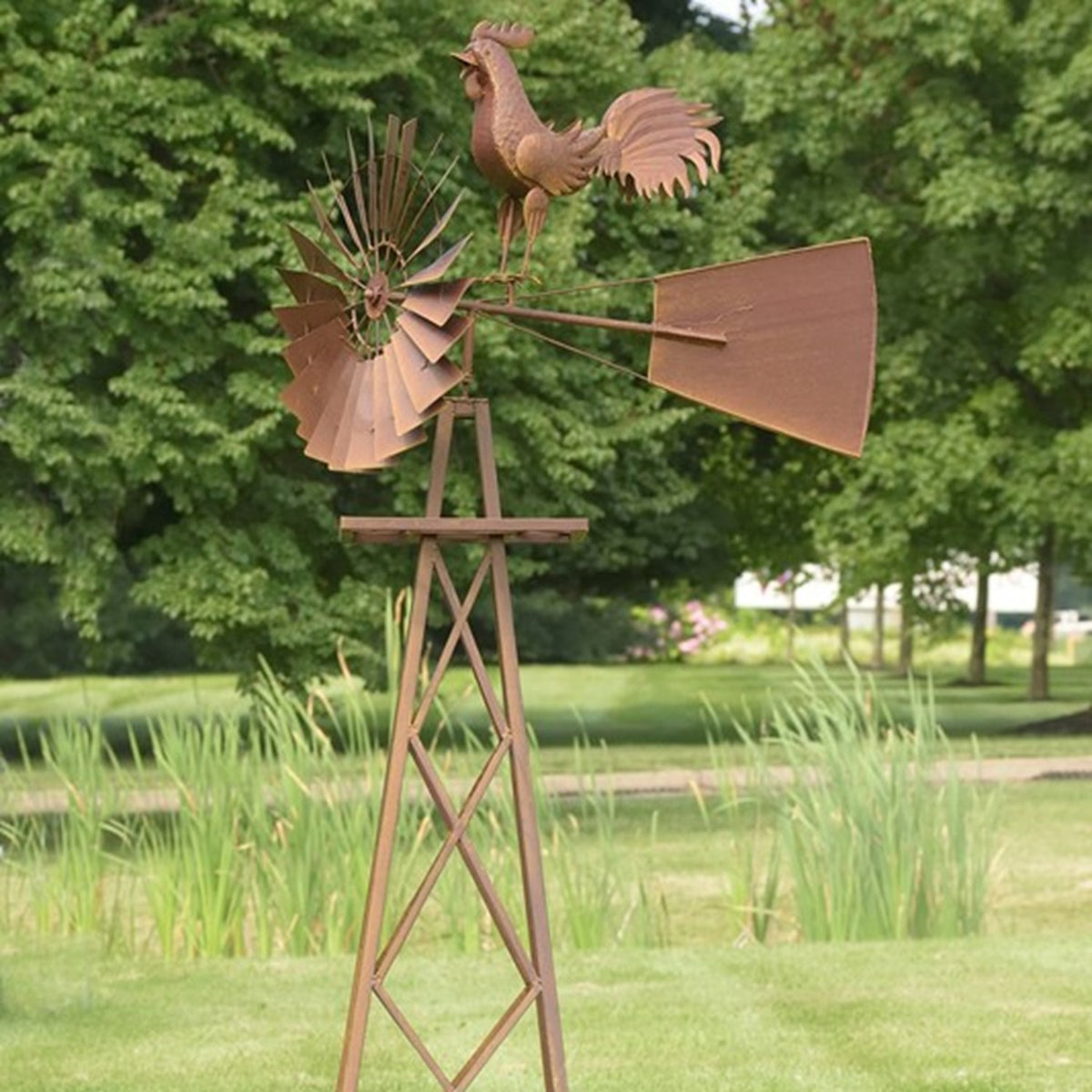 Windmill stand and rooster shown from another angle in a grassy garden.