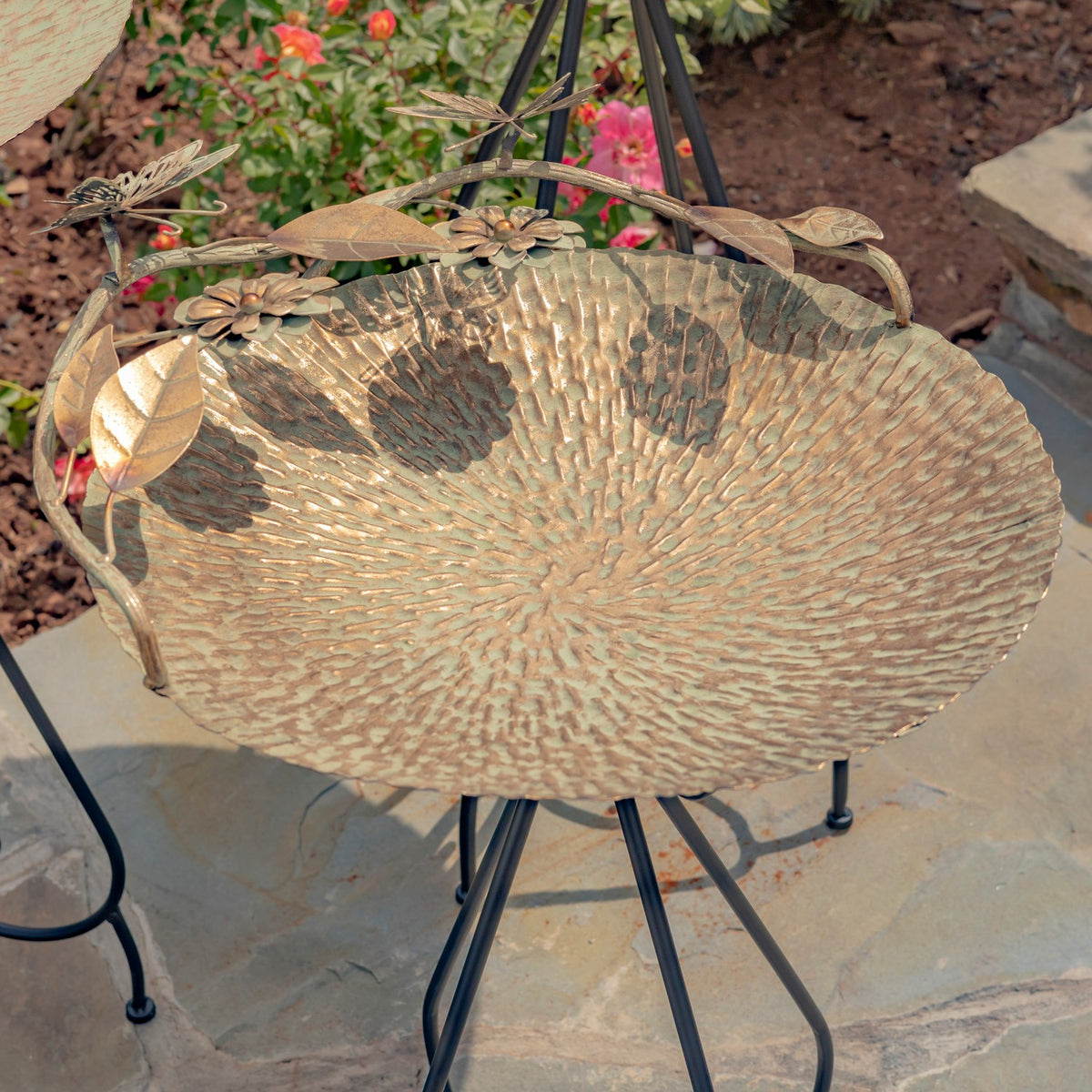 Gold birdbath on a black metal stand, with leaf, flower, and butterfly ornaments around the rim.
