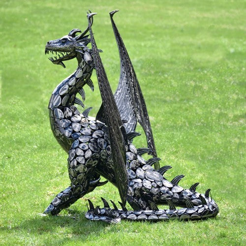 Side view showing the dragon’s scaled body, tall wings, and long spiked tail resting on grass.