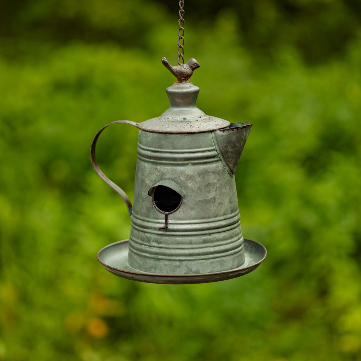 Ridged teapot birdhouse with a round entrance, short spout, arched handle, and bird finial on its lid.