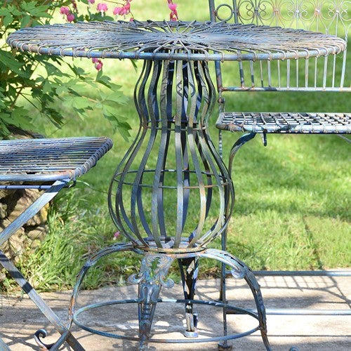Close view of the round woven metal tabletop and its sculptural curved pedestal base.