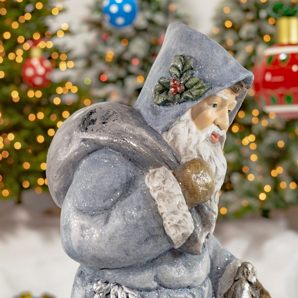 Side view of blue-gray hooded Santa carrying a rounded bag over his shoulder