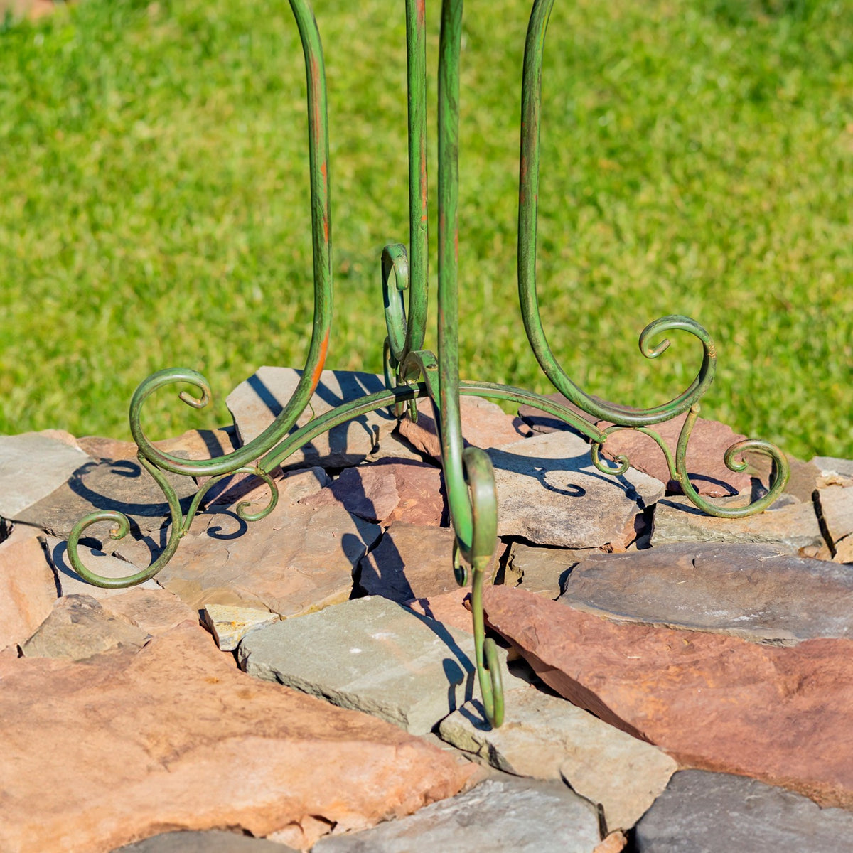 Close-up of the stand’s curled metal feet resting on a stone surface.