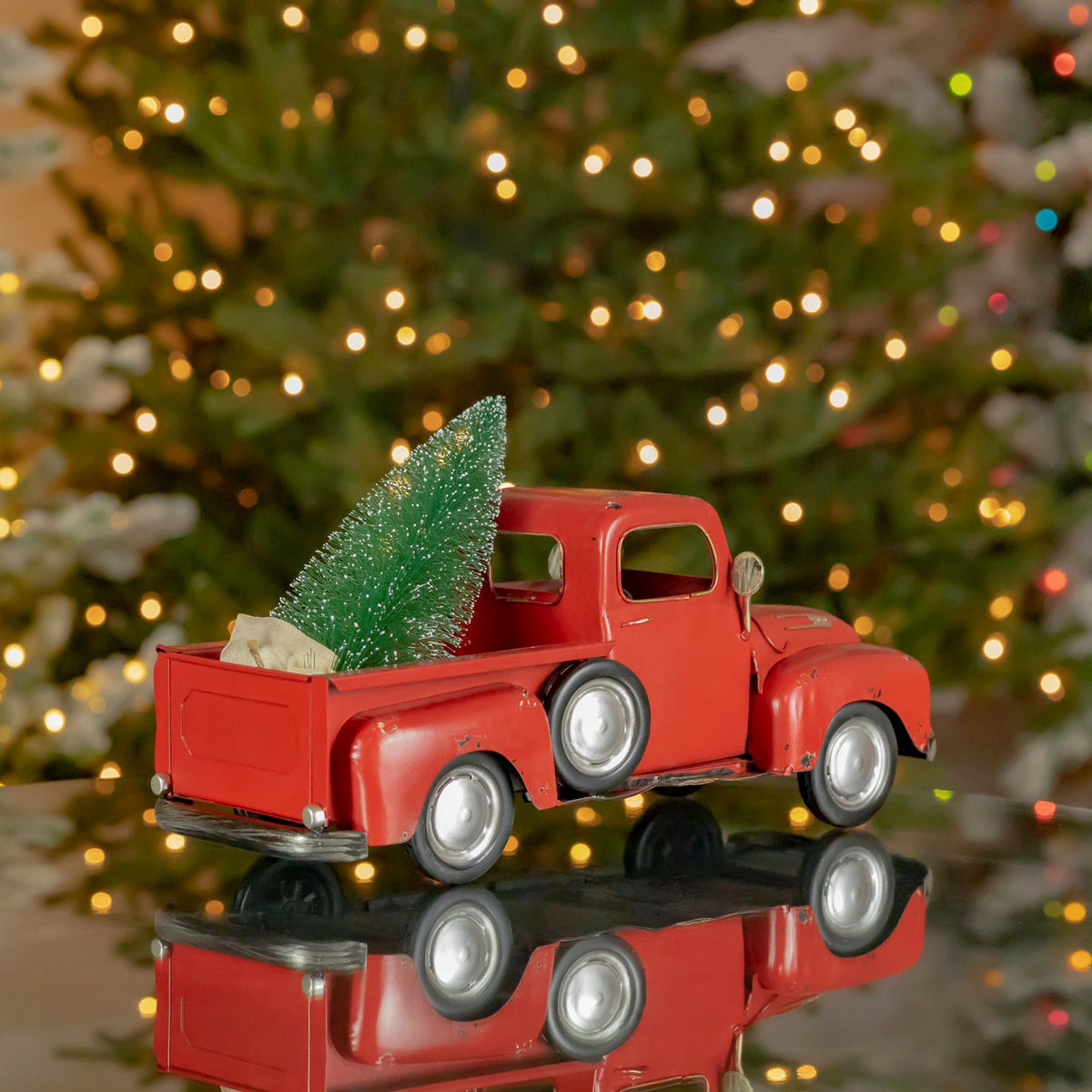 Rear view of the red pickup with a green tree and pale bundle in the truck bed.