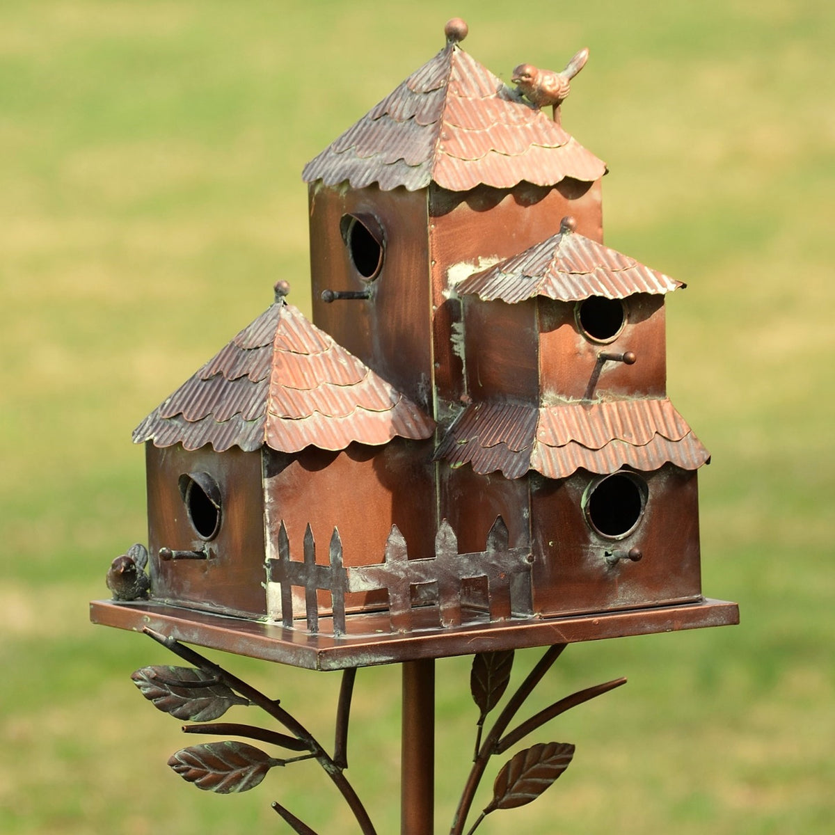 Closer view of the metal birdhouse tops, round entry holes, fence-like trim and small bird figures.