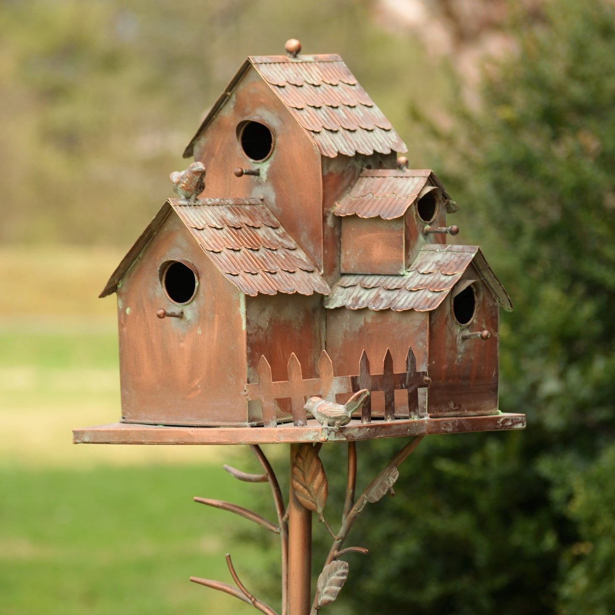 Antique copper birdhouse stake with several entry holes, photographed outdoors