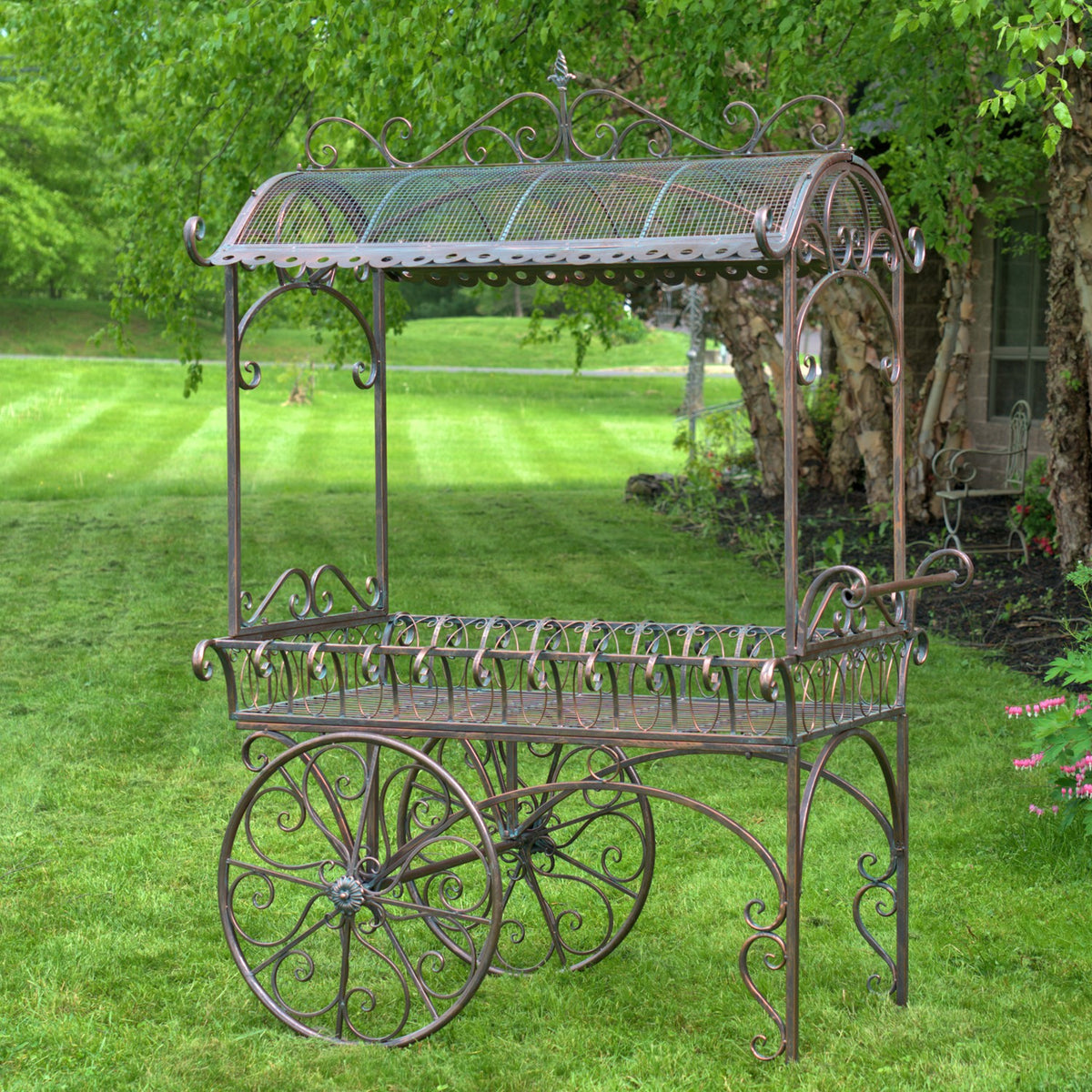 Full view of the iron flower cart on a lawn, showing its roof, raised tray and large wheels.