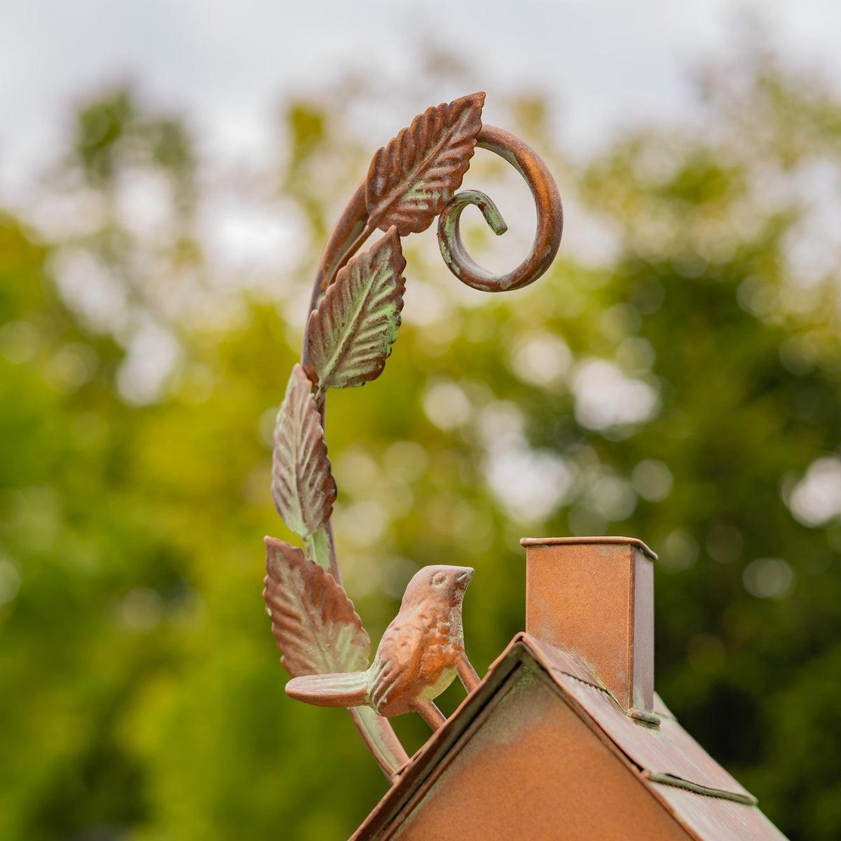 Close-up of decorative leaf curl and bird detail above the birdhouse roof