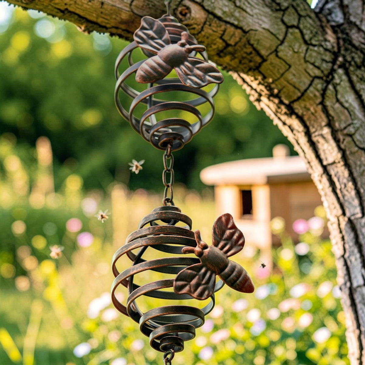 Close view of two bee-shaped ornaments attached to bronze-toned spiral cups hanging from a tree.
