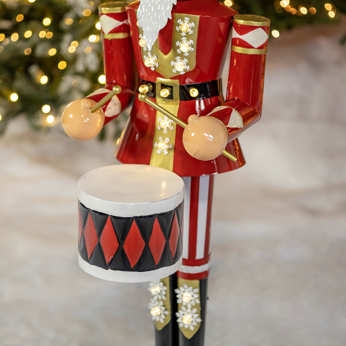 Close-up of the nutcracker’s hands and drum, showing its diamond-patterned sides and lit trim.