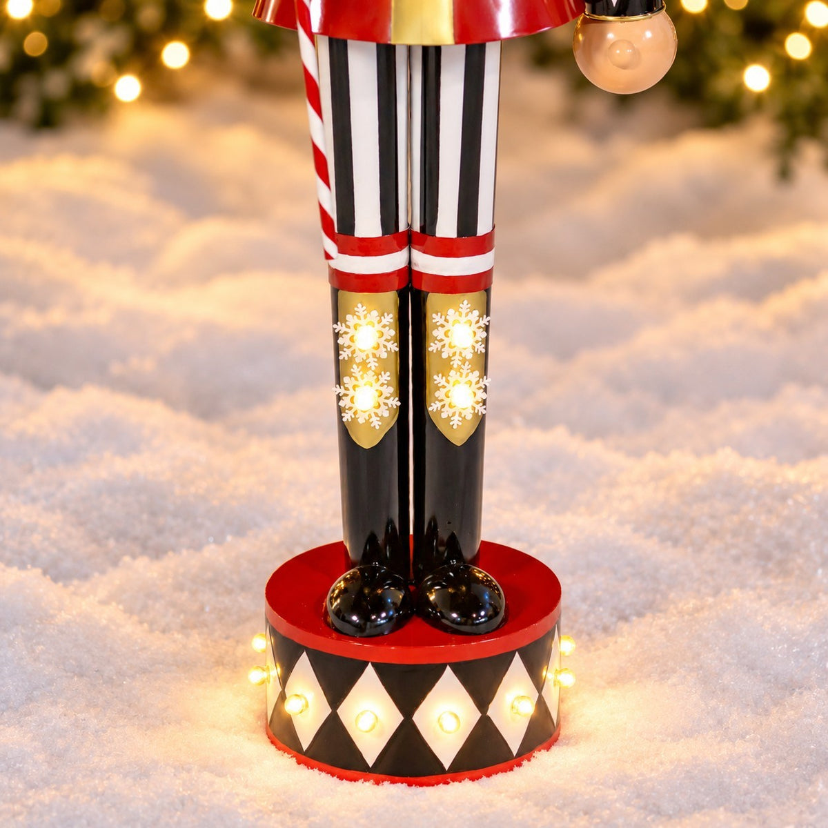 Close view of striped trousers, illuminated boots, and the decorated round base on snow.