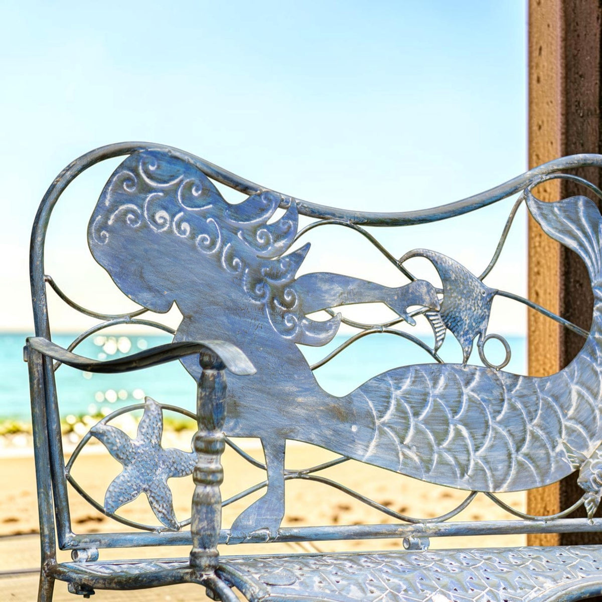 Close-up of the mermaid figure, starfish, and textured blue metalwork on the bench back.