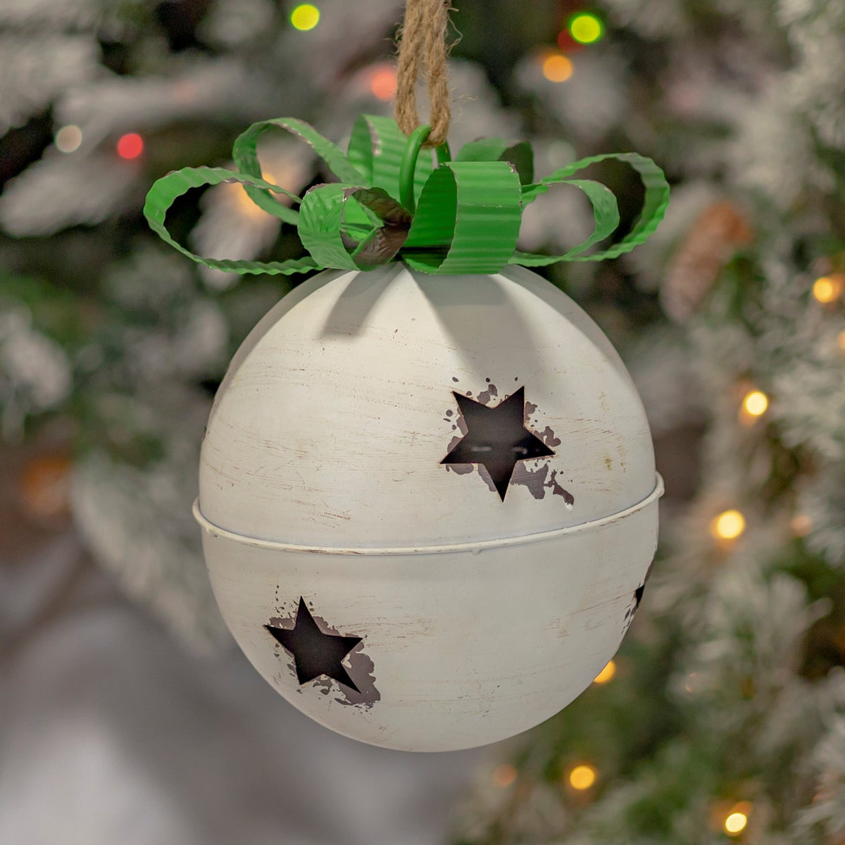 Distressed cream hanging bell with star cutouts and a green bow